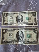 Fronts of both 1976 $2 notes showing serials and condition