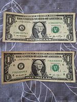 Fronts of both $1 notes showing serials, seals, and wear