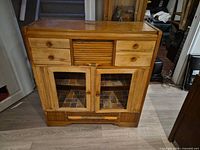 Front view showing overall cabinet layout: drawers, tambour door, glass doors, lower drawer