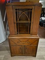 Front view of two-piece hutch showing glass door, drawer and cabinet doors