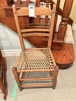 Full front view of wooden ladder back chair showing woven seat