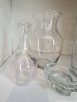 Group of three clear glass vessels including bud vase, flared vase and hexagonal bowl