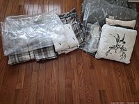Plaid bedding, grey wildlife-print bedding in plastic bags, white embroidered cushion visible