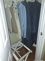 Closet view showing vest, denim shirt, fleece jackets, bathrobes and folding luggage rack