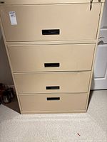 Front view of beige four-drawer metal filing cabinet