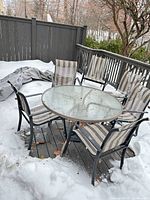 Round glass patio table with six chairs and umbrella stand on deck