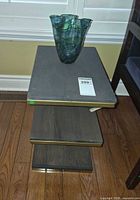 Full view of three-tier side table with vase on top
