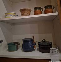 Cabinet view showing all seven pottery pieces on two shelves