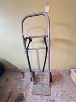 Full view of gray upright moving dolly against wall