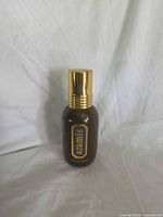 Front view showing Aramis logo on brown bottle with gold cap