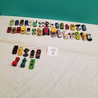 Full overview of the 38 assorted toy cars arranged in rows on a white cloth surface.