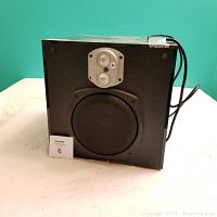 Front and slightly angled view of black Energy subwoofer speaker showing speaker driver and smaller speaker above it, cord wrapped on side.