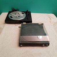 Image shows two turntables placed on a cloth-covered surface, with the Sanyo turntable in the back and the Sony turntable in the foreground with its dust cover on.
