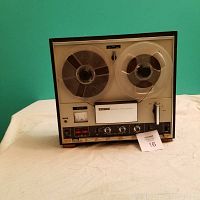 Front view of Sony reel-to-reel tape recorder with tape reels mounted and control panel visible.