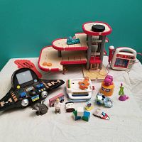 Full view of the various small children's toys for sale including wooden garage, spaceship, toy radio and figurines.