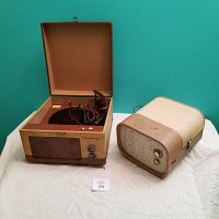 Pair of suitcase record players including Seabreeze with open lid and Symphonic unit beside it on white cloth.