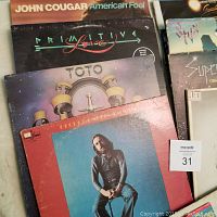 Photo showing records by John Cougar Mellencamp, Primitive Love (Miami Sound Machine), Toto, George Benson.