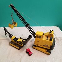 Photo showing the two large yellow Tonka construction toys and two small red toy vehicles on a white surface.