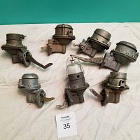 Full lot of 6 rebuilt mechanical fuel pumps on a white cloth background, showing various angles and features.