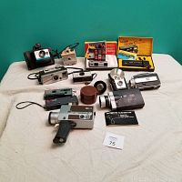 Full view of the lot showing multiple vintage cameras including Kodak Pocket Instamatic and Ektralite, several movie cameras, flash units, and original boxes.