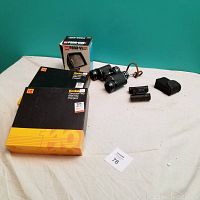 Lot laid out showing large binoculars, small Bushmaster binoculars, two Kodak Carousel 140 slide trays, Kodak Pana-Vue slide viewer in box, and a black slide carousel viewer.