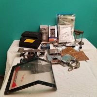 Photo showing rubber tire stops, vacuum bags, metal brackets, and Legacy speaker cover on a white surface against teal wall.