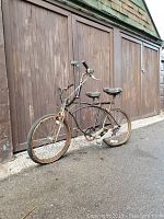 Full side view of the side-by-side tandem bicycle showing black frame, two seats, two sets of handlebars, and tires with wear.