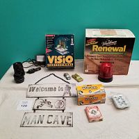 Overview of miscellaneous items on table including Varathane box, Visio software box, Man Cave signs, playing cards, Wite-Out box, red beacon light, toy cars, and camera lens parts.