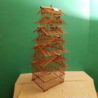 Full frontal photo of the bamboo bird cage showing its tiered structure and pitched roofs.