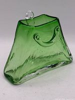 Front view of green purse-shaped glass vase showing handle detail and color