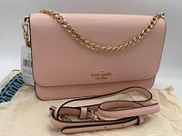 Full view of crossbody showing front flap, chain strap, extra leather strap, hang tag