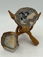 Front view showing geode half on stand with polished agate freeform beside