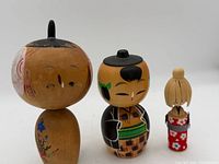 Front view of three kokeshi dolls showing sizes and painted details