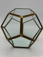 Front view showing glass pentagon panels and brass frame