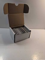 Open cardboard storage box showing stack of TCG cards