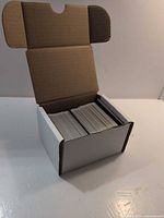Closed white cardboard storage box showing stacked cards inside