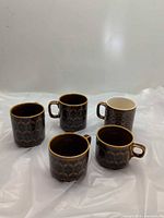 Five brown patterned mugs side by side