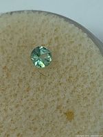 Round green alexandrite gem on foam pad