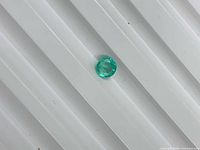Round green emerald on white ridged background
