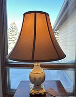 Full view of lamp showing glass base, gold accents, fabric shade and power cord