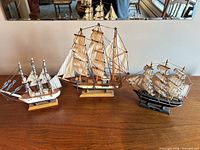 Front view of all three tabletop model ships on wooden surface