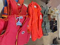 Group shot of vests, coat, waders, tackle boxes on table