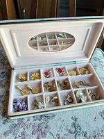 Open pastel jewelry case showing all earrings and pendants in compartments