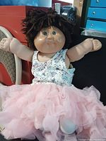 Front view of Cabbage Patch Kids doll seated with arms outstretched