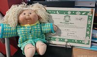 Front view of doll seated beside adoption papers