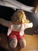 Front view of blond Cabbage Patch Kids doll seated on desk