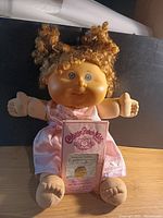 Full view of doll seated with birth certificate card