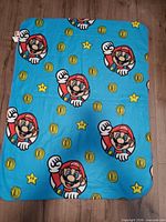 Blue fleece throw with Mario faces, coins, stars full view