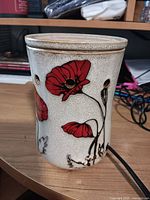 Front view of ceramic wax melt warmer showing poppy design and power cord