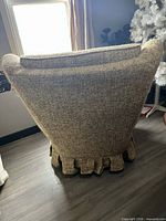 Rear view of textured fabric armchair showing pleated skirt and curved back